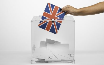 person putting united kingdom flag card into ballot box