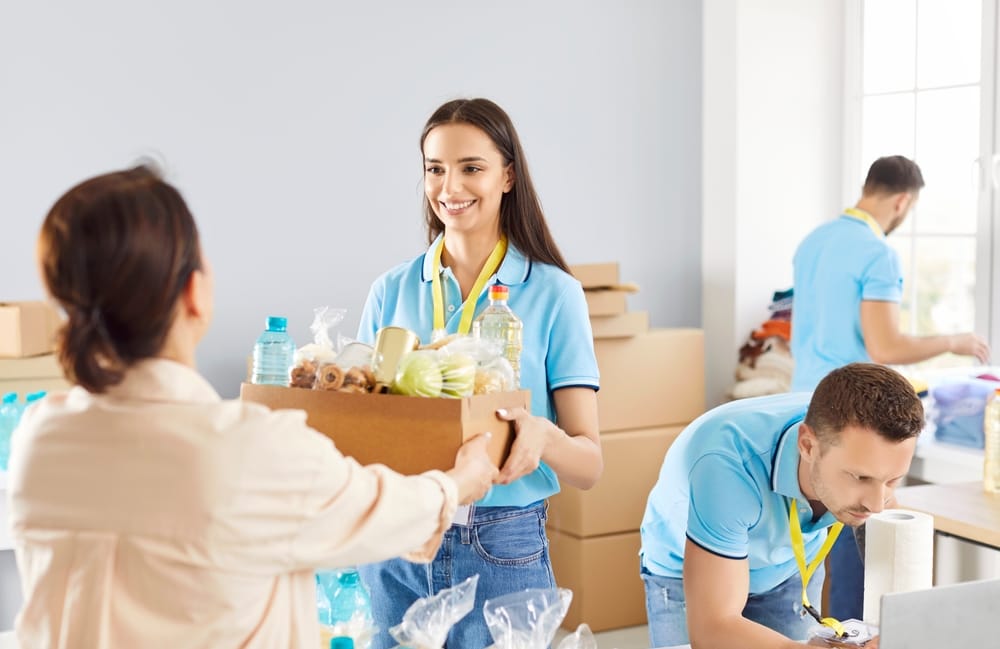 Young,Cheerful,Volunteer,Working,At,Charity,Center,And,Giving,Free