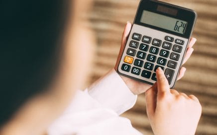 Businesswoman counting with calculator in office