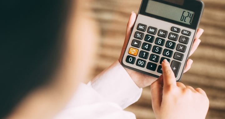 Businesswoman counting with calculator in office